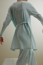 back of women in pale blue ribbed cardigan and pants