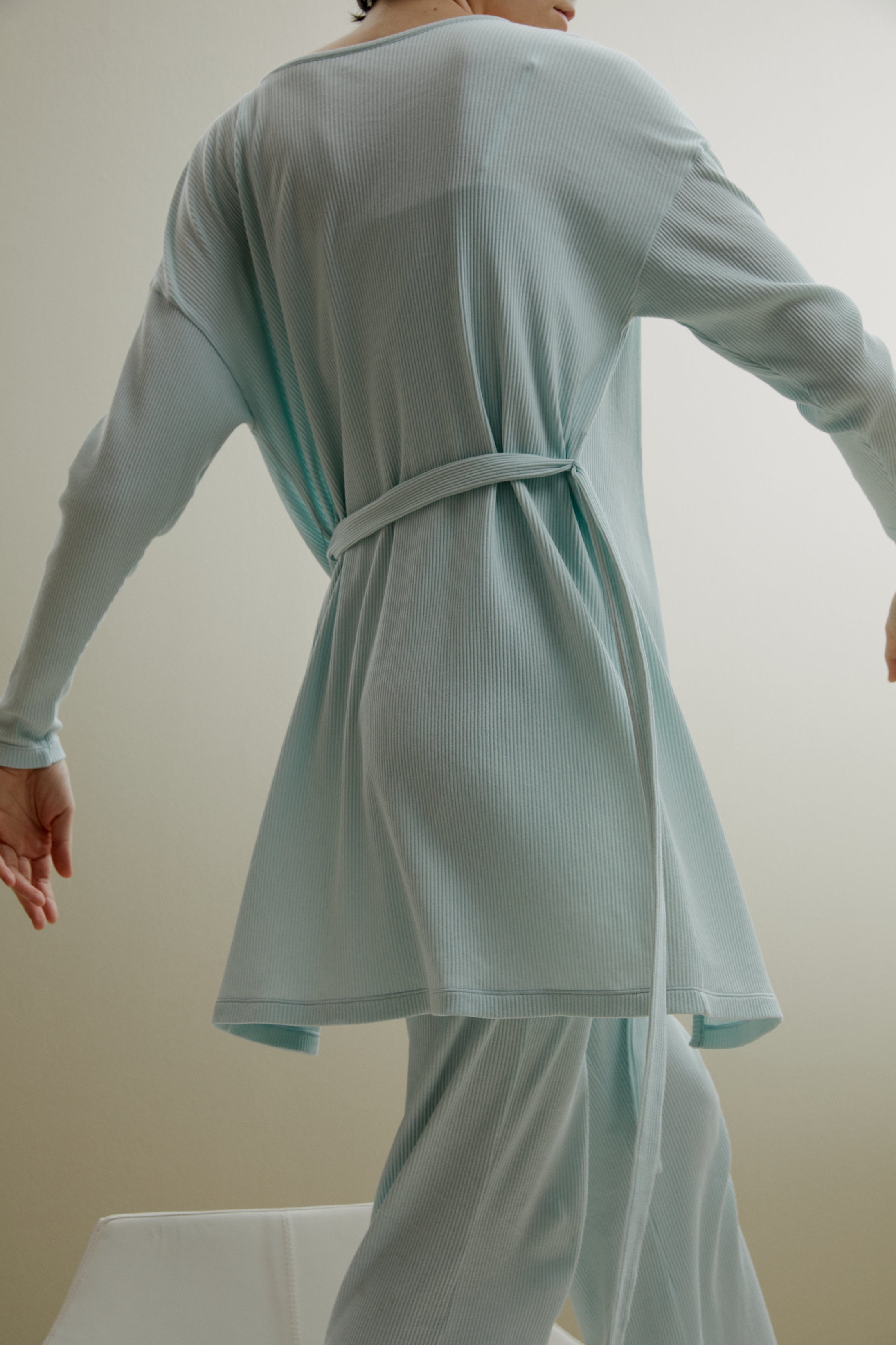 back of women in pale blue ribbed cardigan and pants