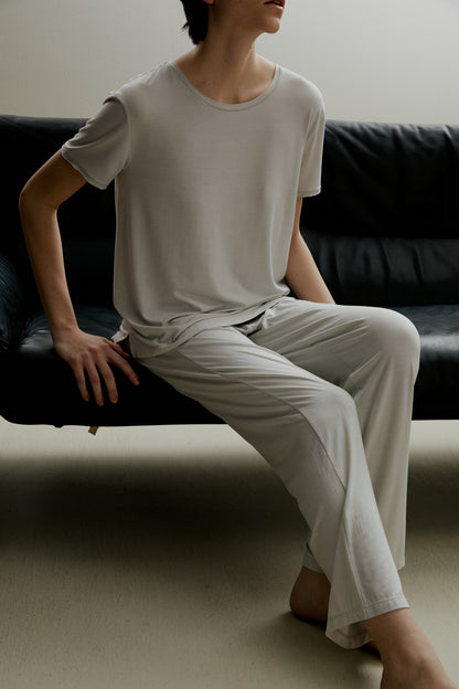 Woman sitting wearing light gray short sleeve pajama shirt and matching pants