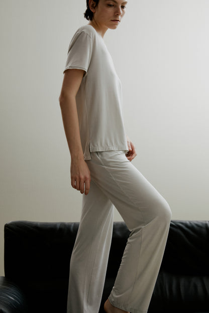 Side view of woman wearing light gray short sleeve pajama shirt and matching pants