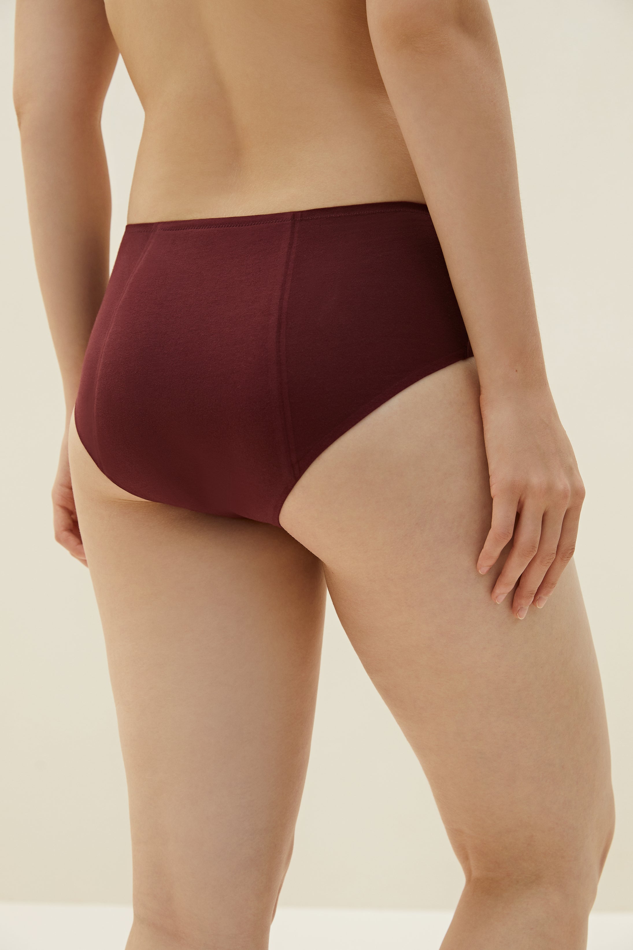 Back of bottom half of woman wearing burgundy briefs with padding in the back
