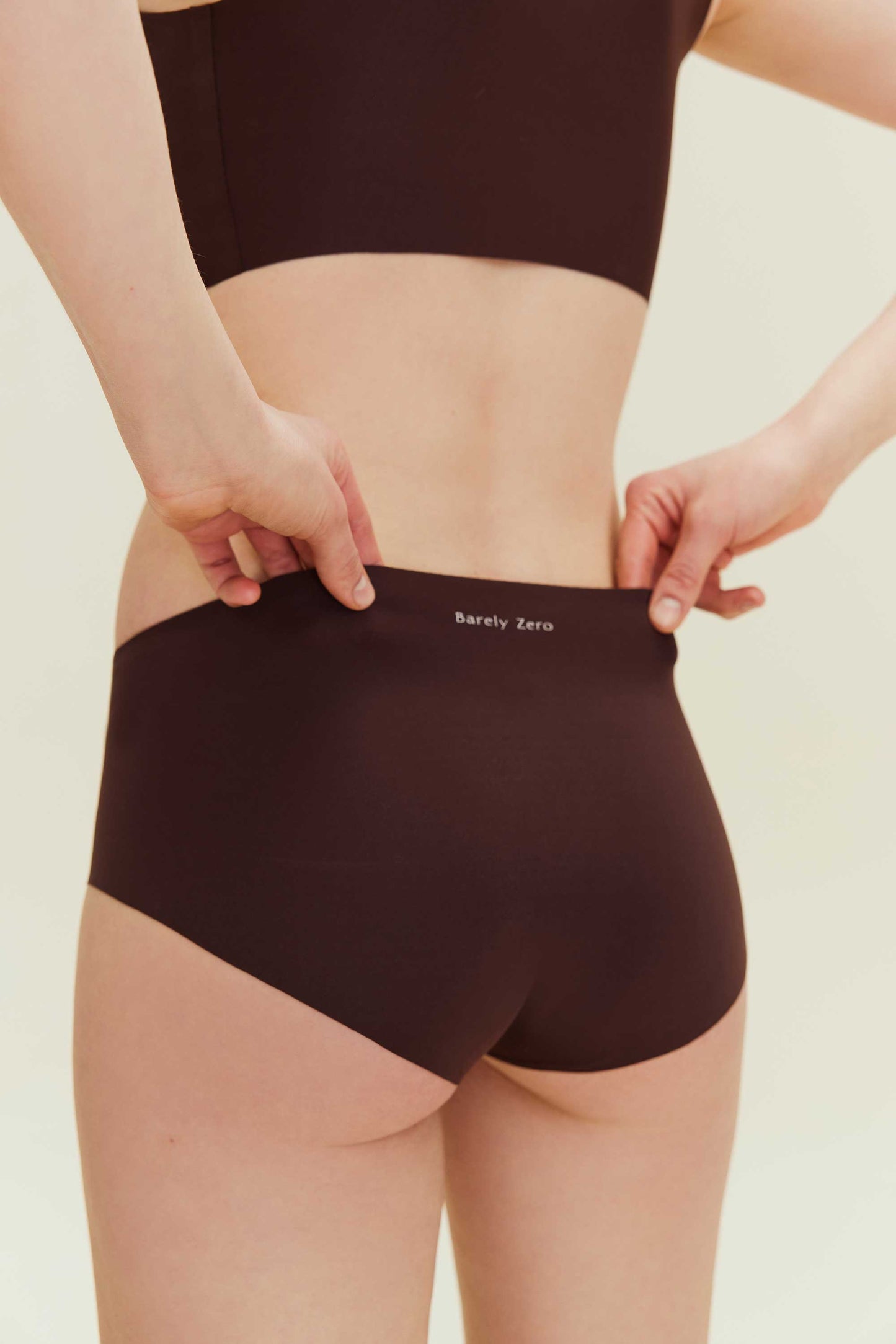 back of woman in brown underwear with Barely Zero printed at the waist