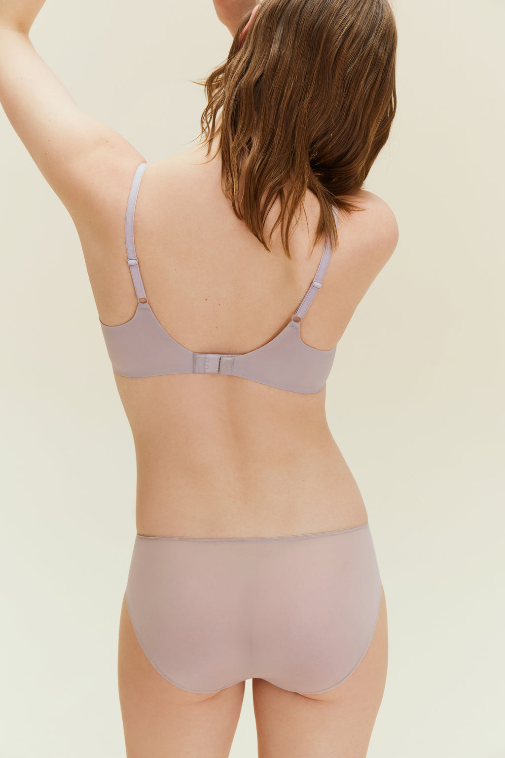 Back view of woman wearing taupe bra and brief.