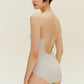 Back view of woman wearing gold one piece swimsuit with spaghetti straps and keyhole neckline design