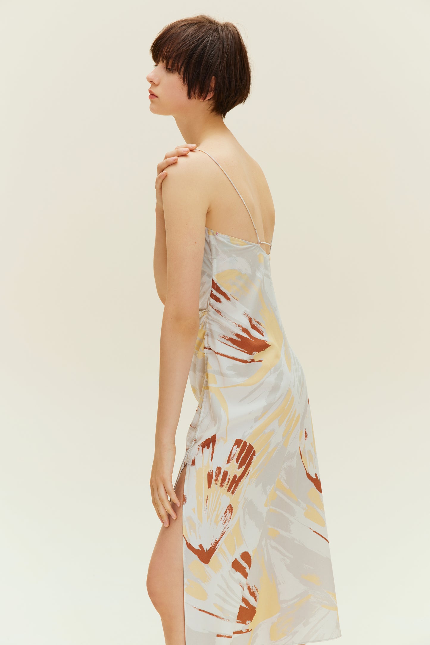 Side view of woman wearing spaghetti strap dress with brown, beige, white print