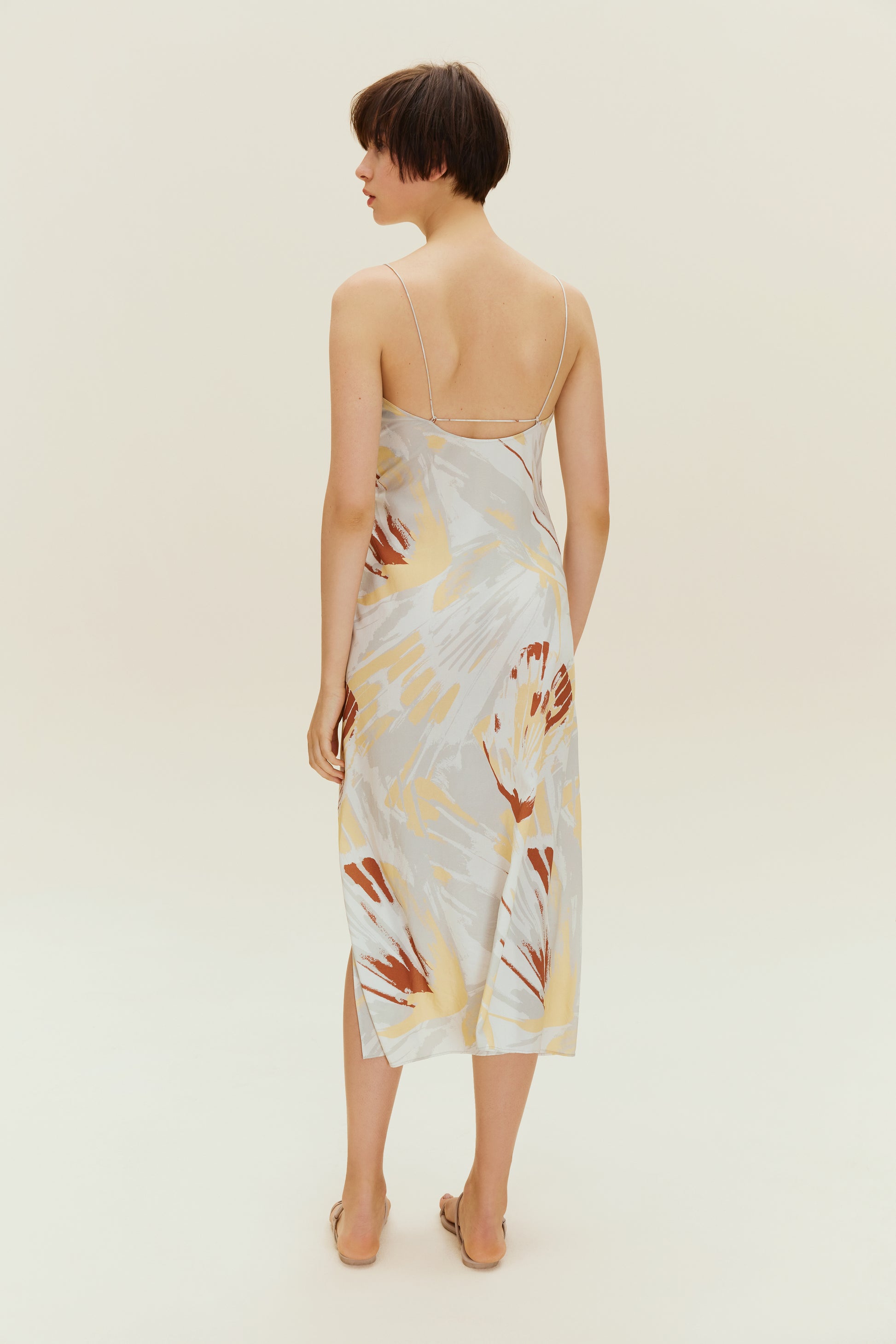 Back view of woman wearing spaghetti strap dress with brown, beige, white print