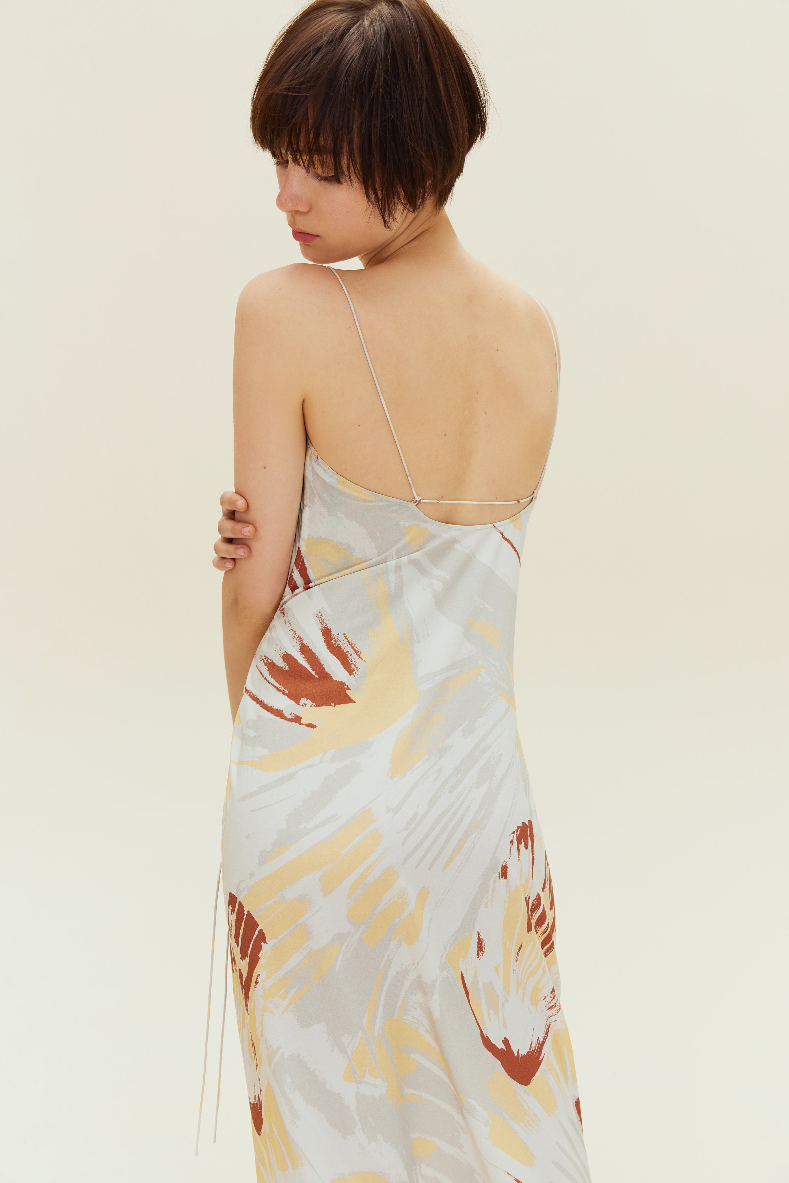 Back view of woman wearing spaghetti strap dress with brown, beige, white print