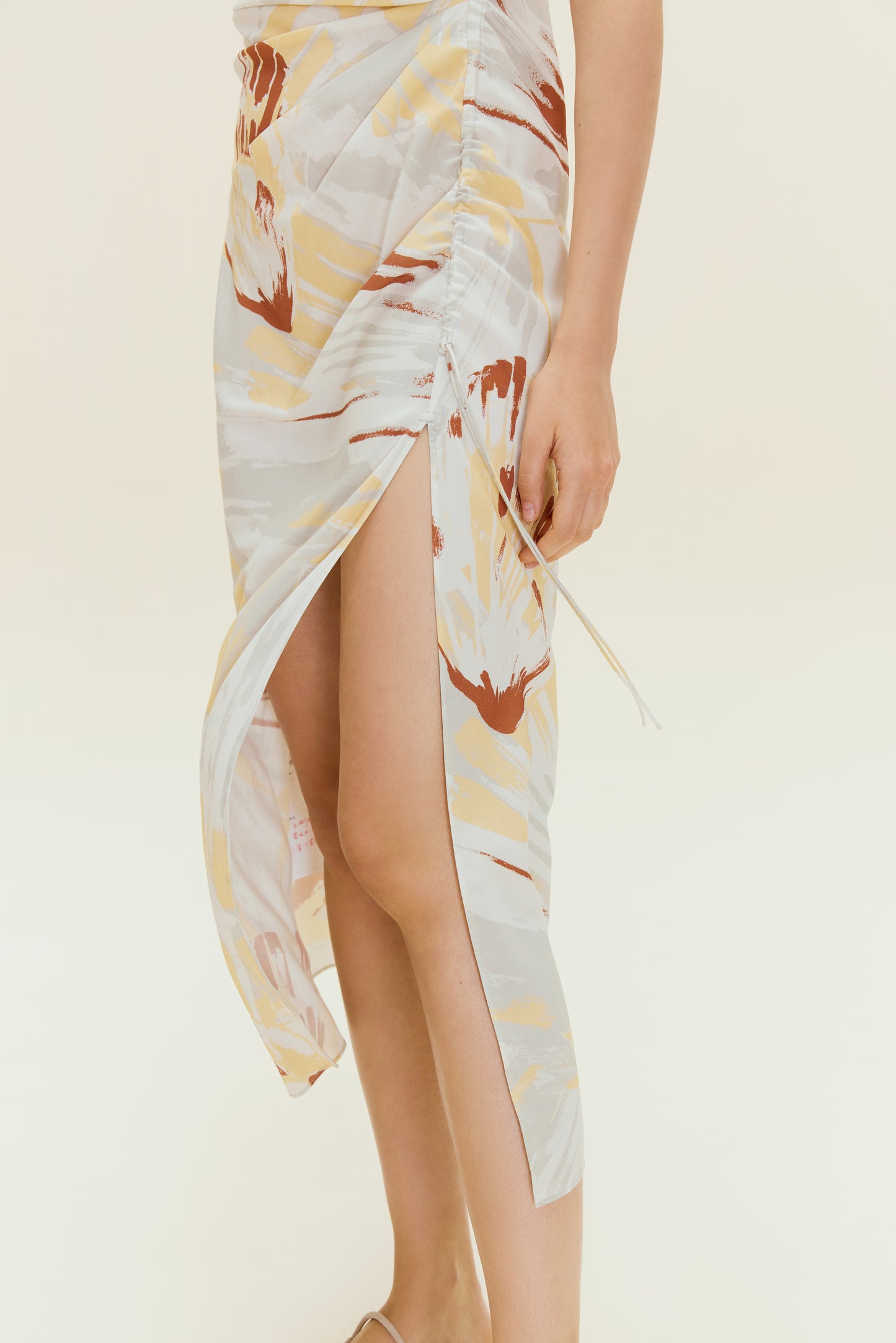 Close up of high slit on dress with brown, beige, white print