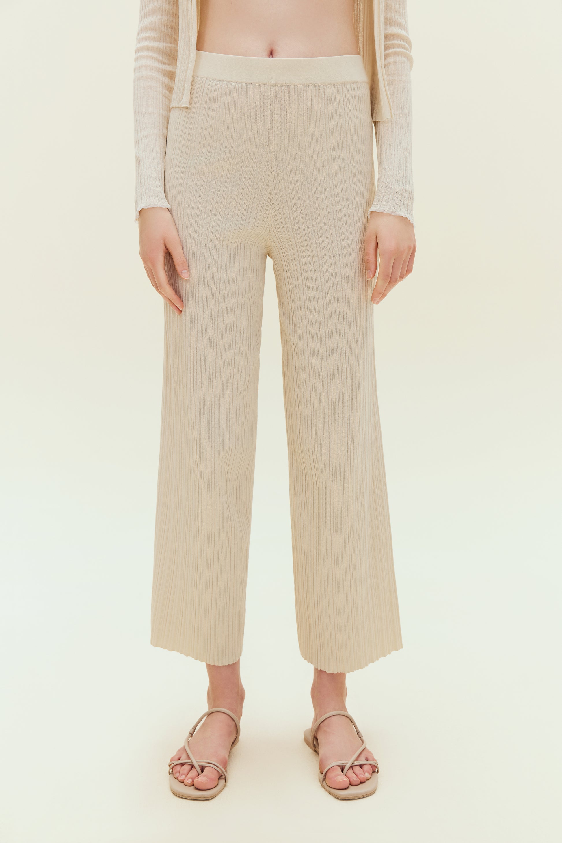 Woman standing wearing off white knit pants