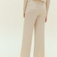 Back view of woman standing wearing off white knit pants with pockets with off white knit cardigan