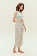 Woman standing wearing light green colored tank top with khaki capris