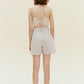 Back view of woman standing wearing beige tank top with khaki shorts