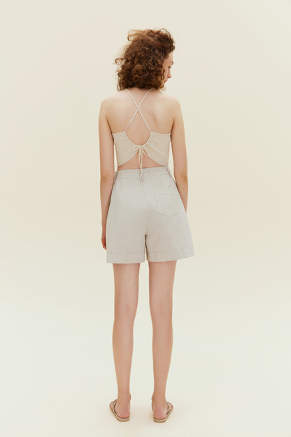 Back view of woman standing wearing beige tank top with khaki shorts