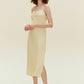 Side view of woman standing wearing cream colored dress with thin straps and high slit on legs