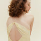 Close up back view of woman wearing cream colored dress with thin straps and cross back design