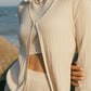 Woman wearing off white knit cardigan with collar over matching tank top and pants