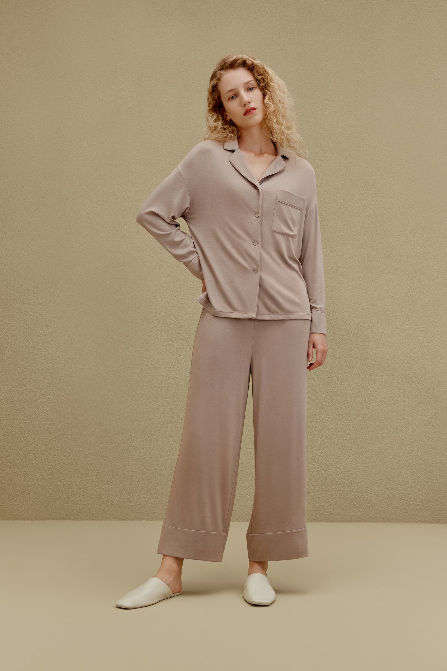 Woman wearing tan button up pajama shirt with pocket and matching pajama pants