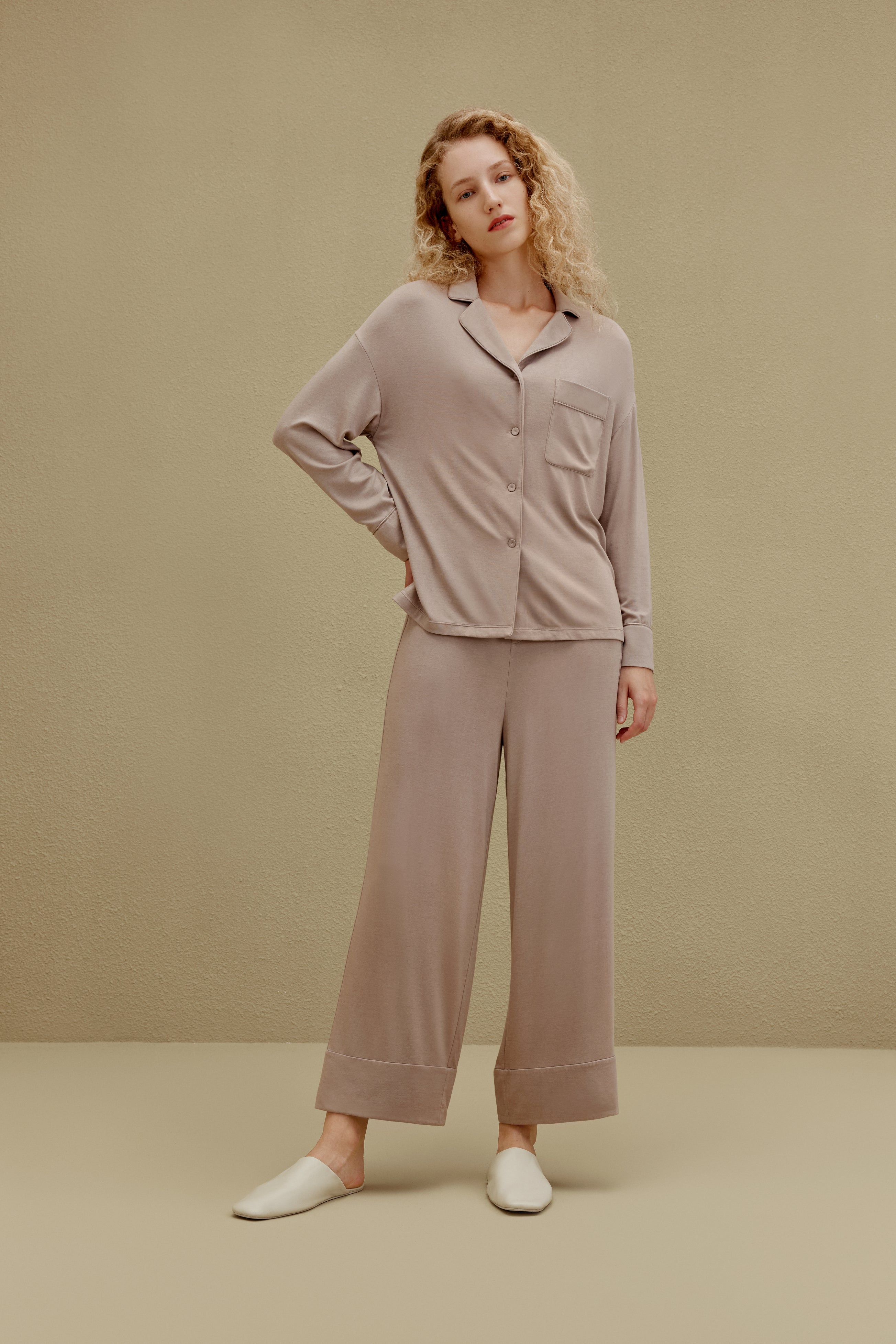 Woman wearing tan button up pajama shirt with pocket and matching pajama pants