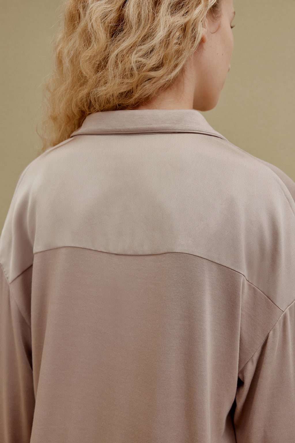 Back view of woman wearing tan pajama shirt