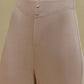 Close up of woman wearing tan pajama pant with two decorative buttons at waist band