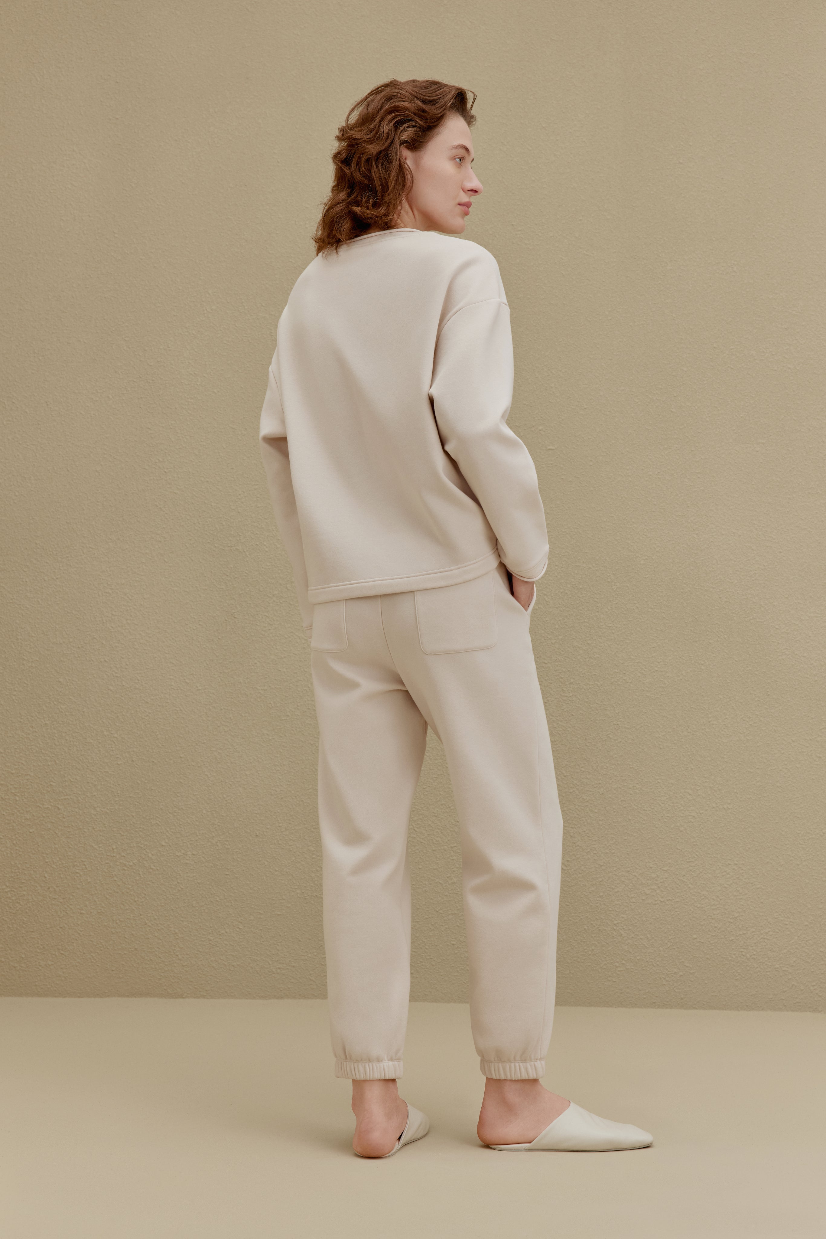 Back of woman in off-white top and pants