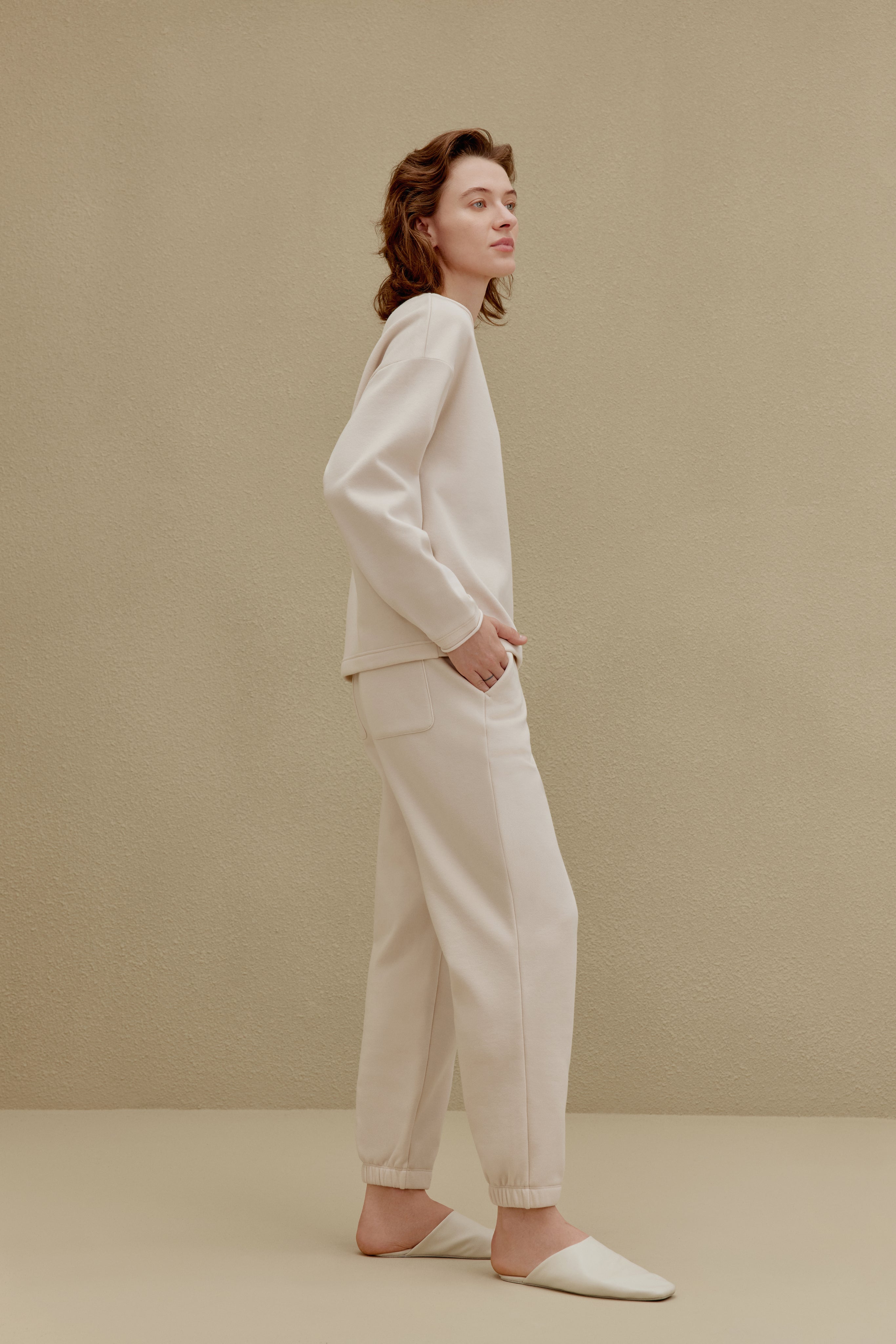 Side view of woman wearing off-white top and pants