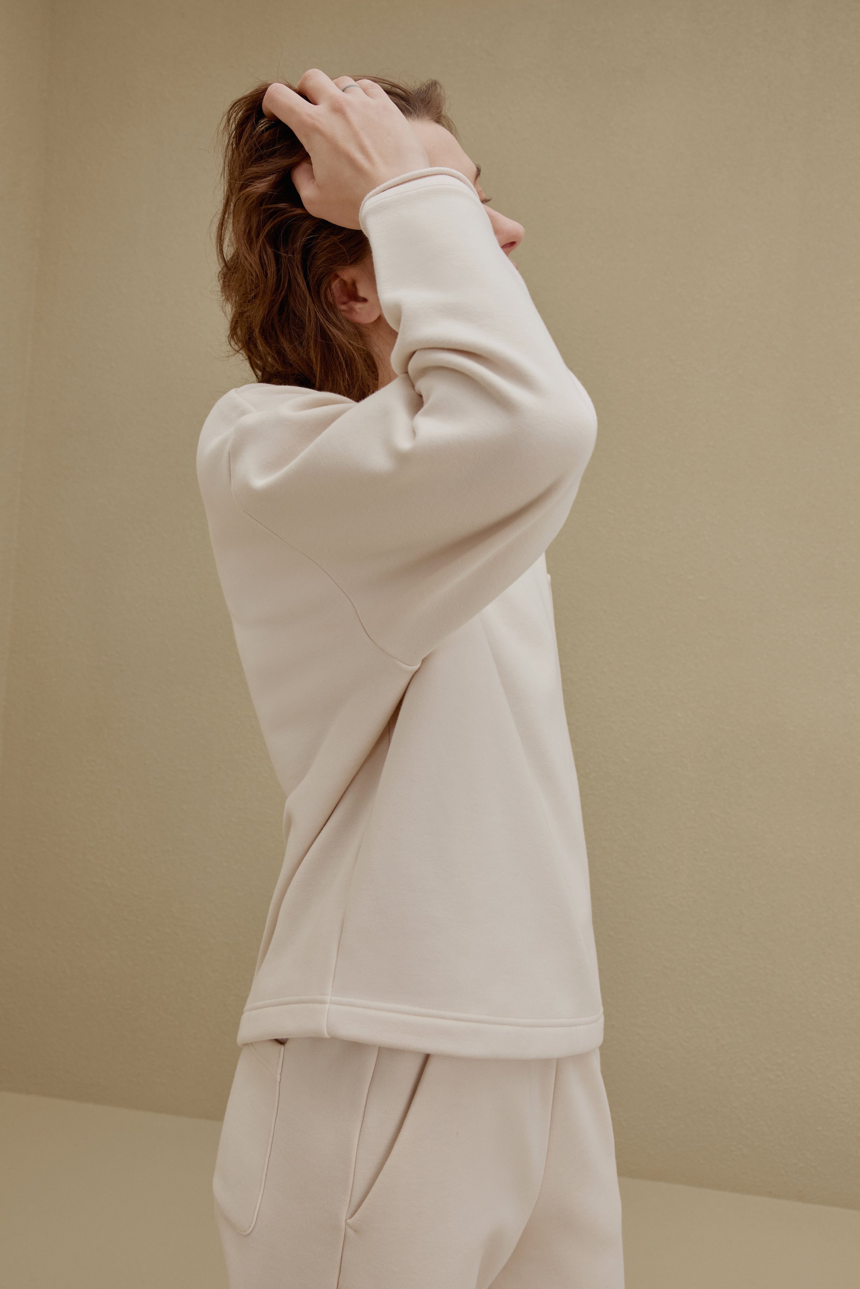 Side view of a woman wearing an off-white top and pants