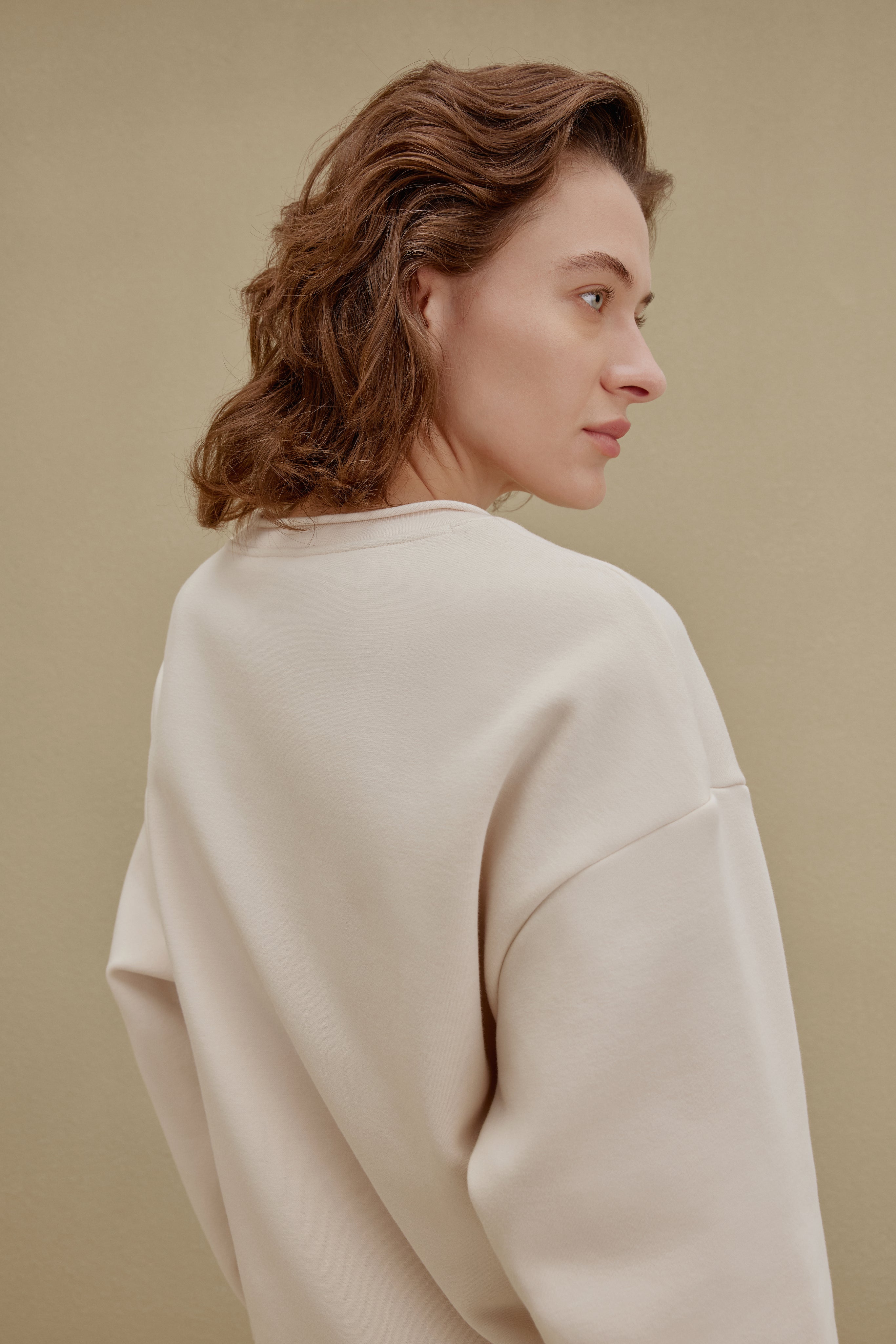 Side view of a woman wearing an off-white top