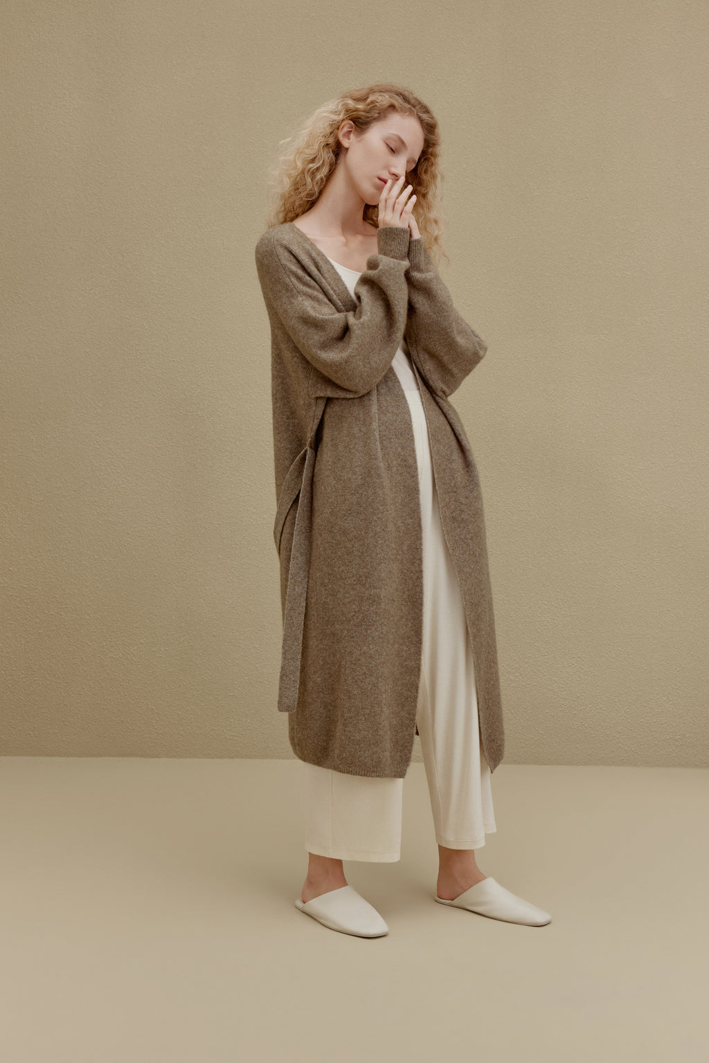  woman in brown long knitted coat and white pants