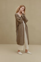 woman in brown long knitted coat and white pants