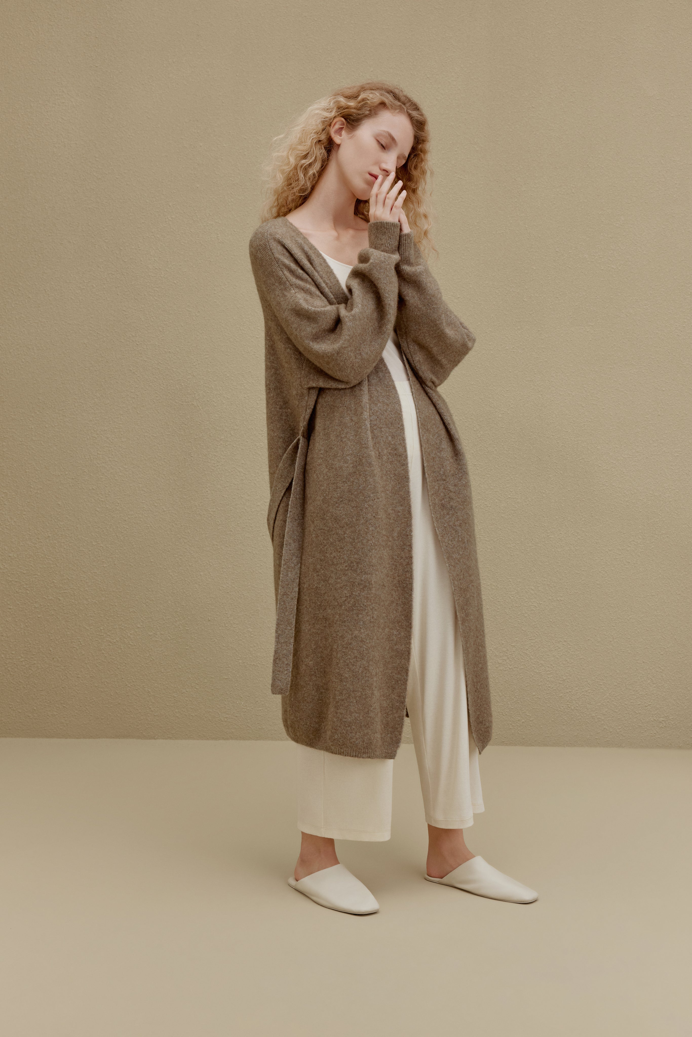  woman in brown long knitted coat and white pants
