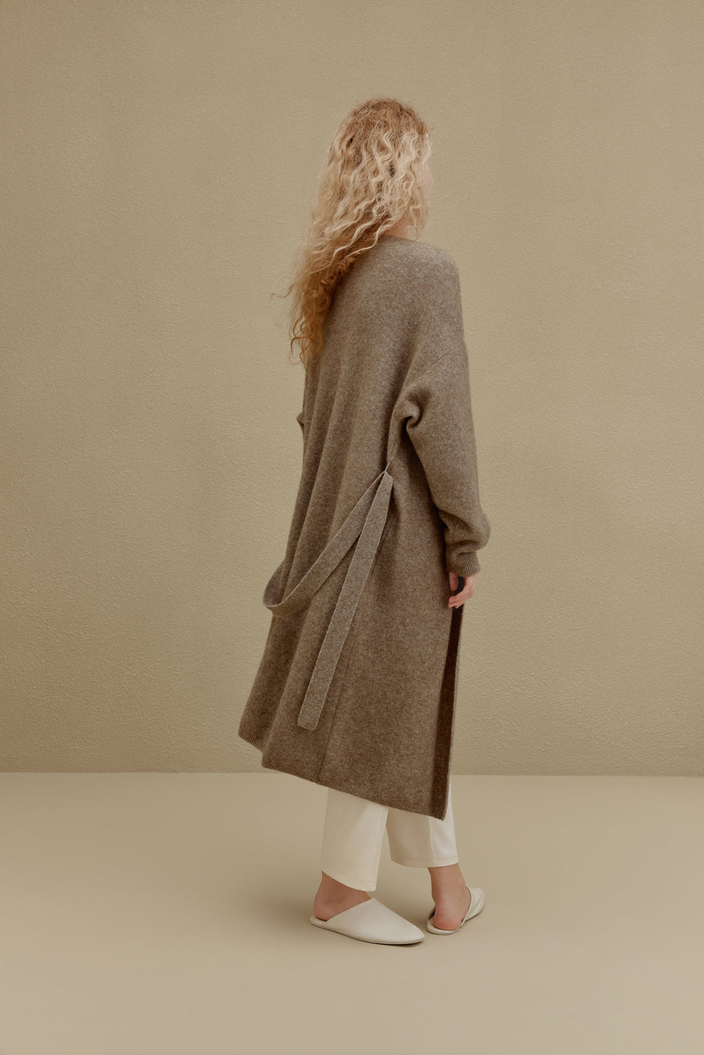 back of woman in brown long knitted coat