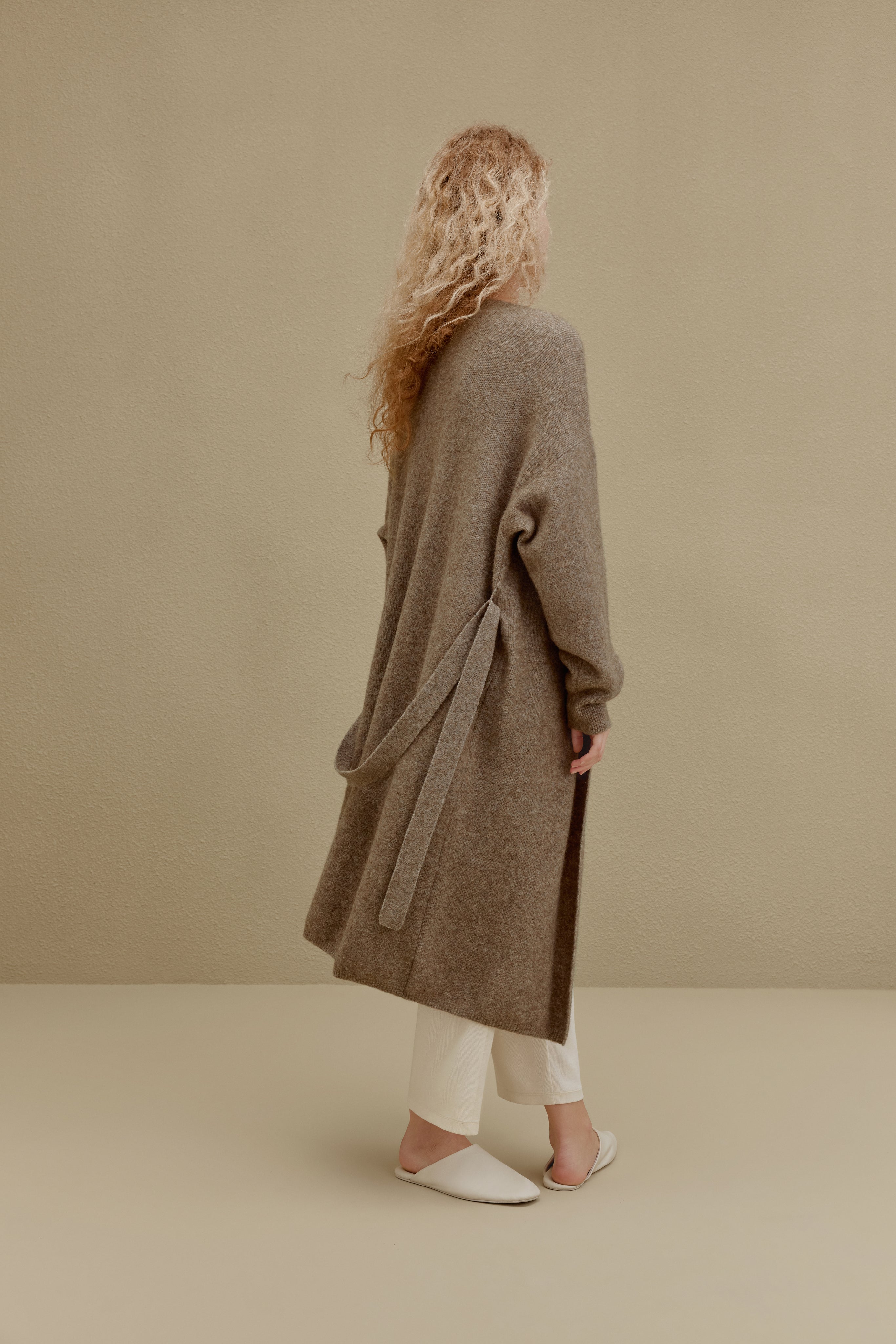 back of woman in brown long knitted coat
