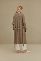 back of woman in brown long knitted coat