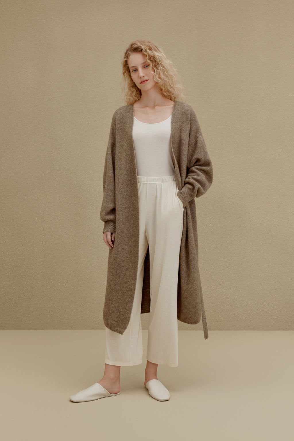  woman in brown long knitted coat and white pants