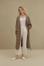  woman in brown long knitted coat and white pants