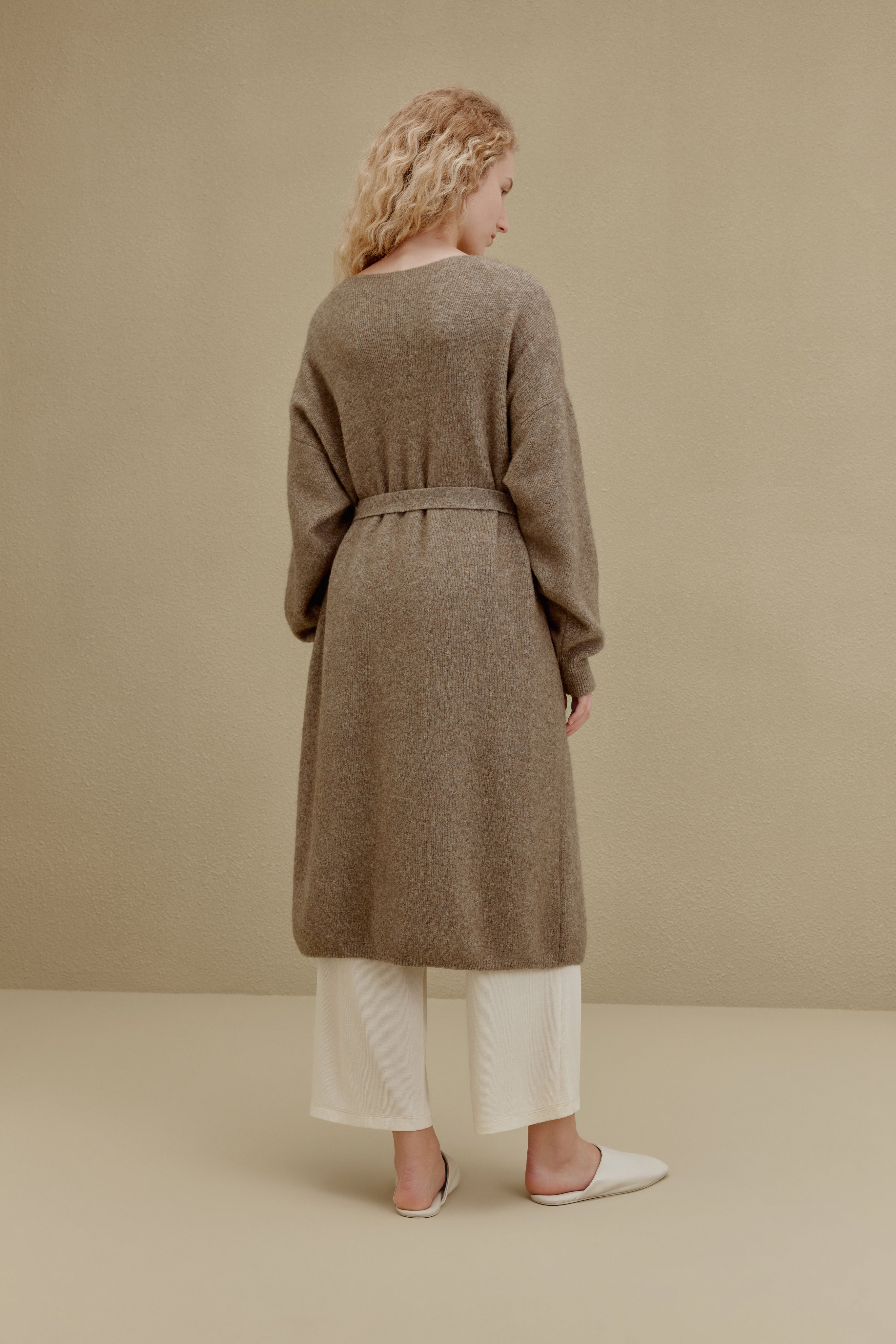 Back of woman in brown long knitted coat