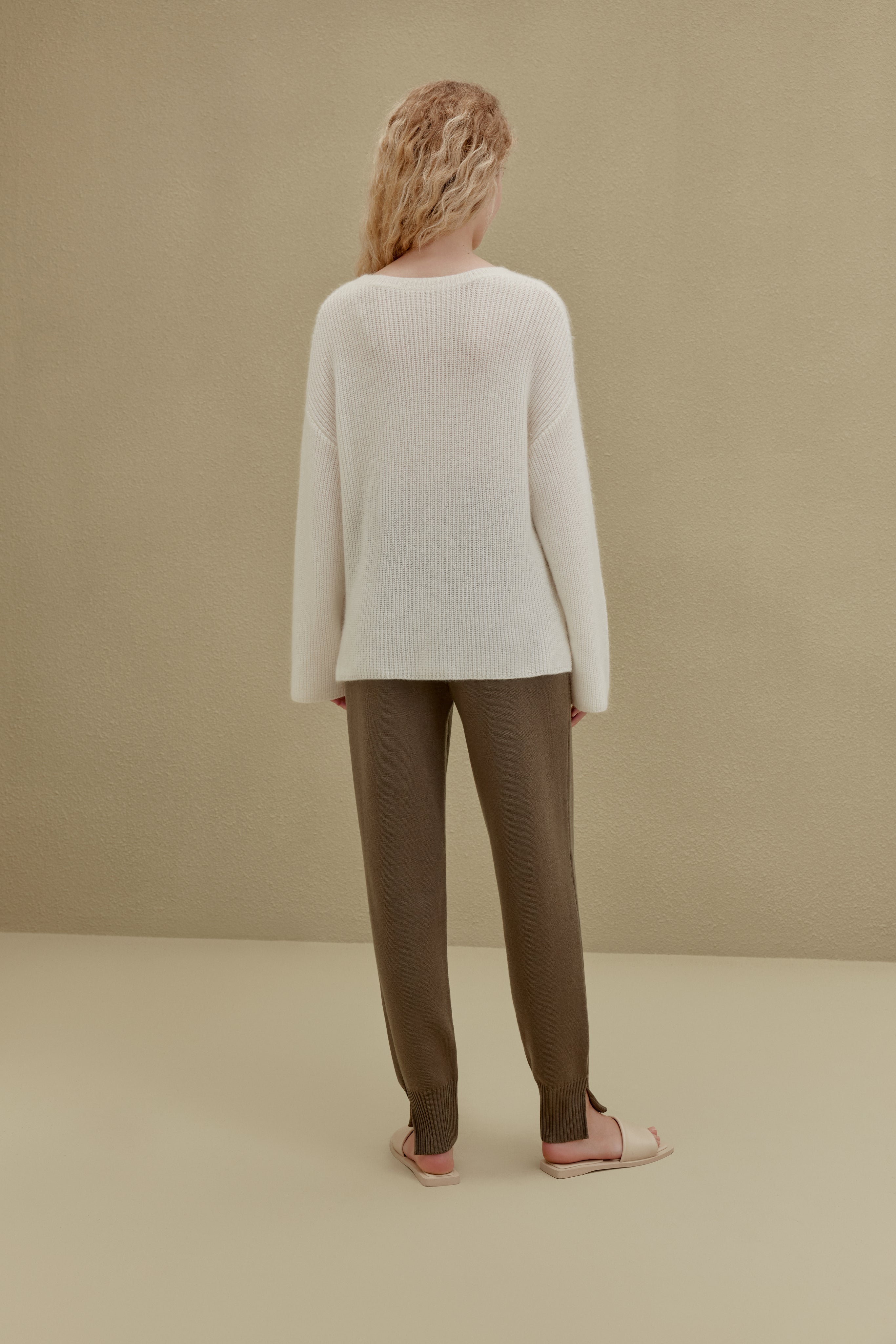 back of women in white knitted top and brown joggers