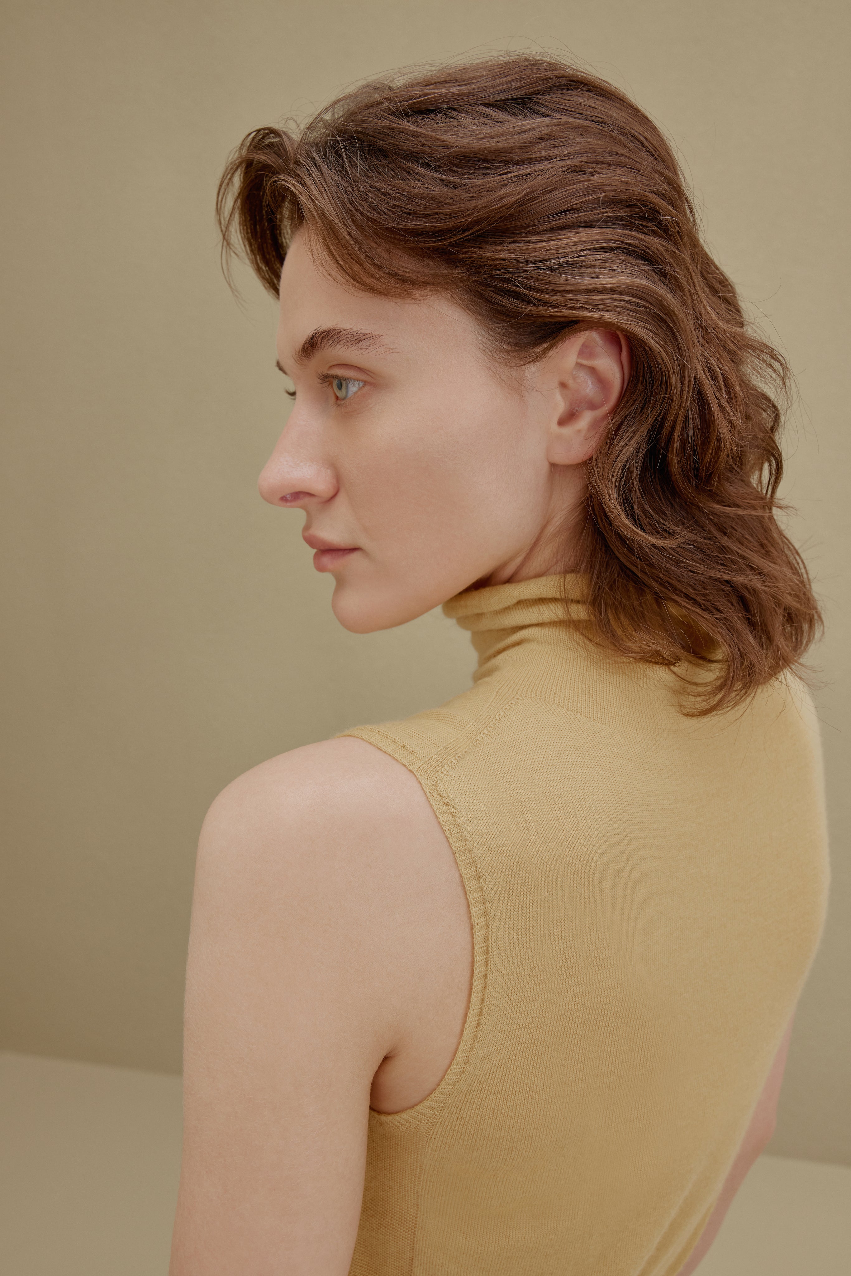Close up of woman in yellow knit turtle neck sleeveless top