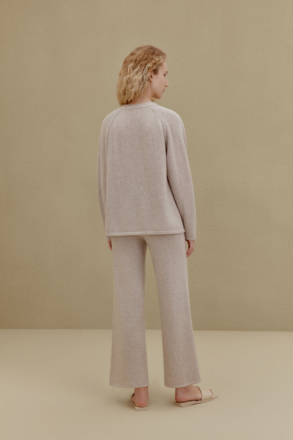 Back view of woman wearing off-white top and wide-leg pants