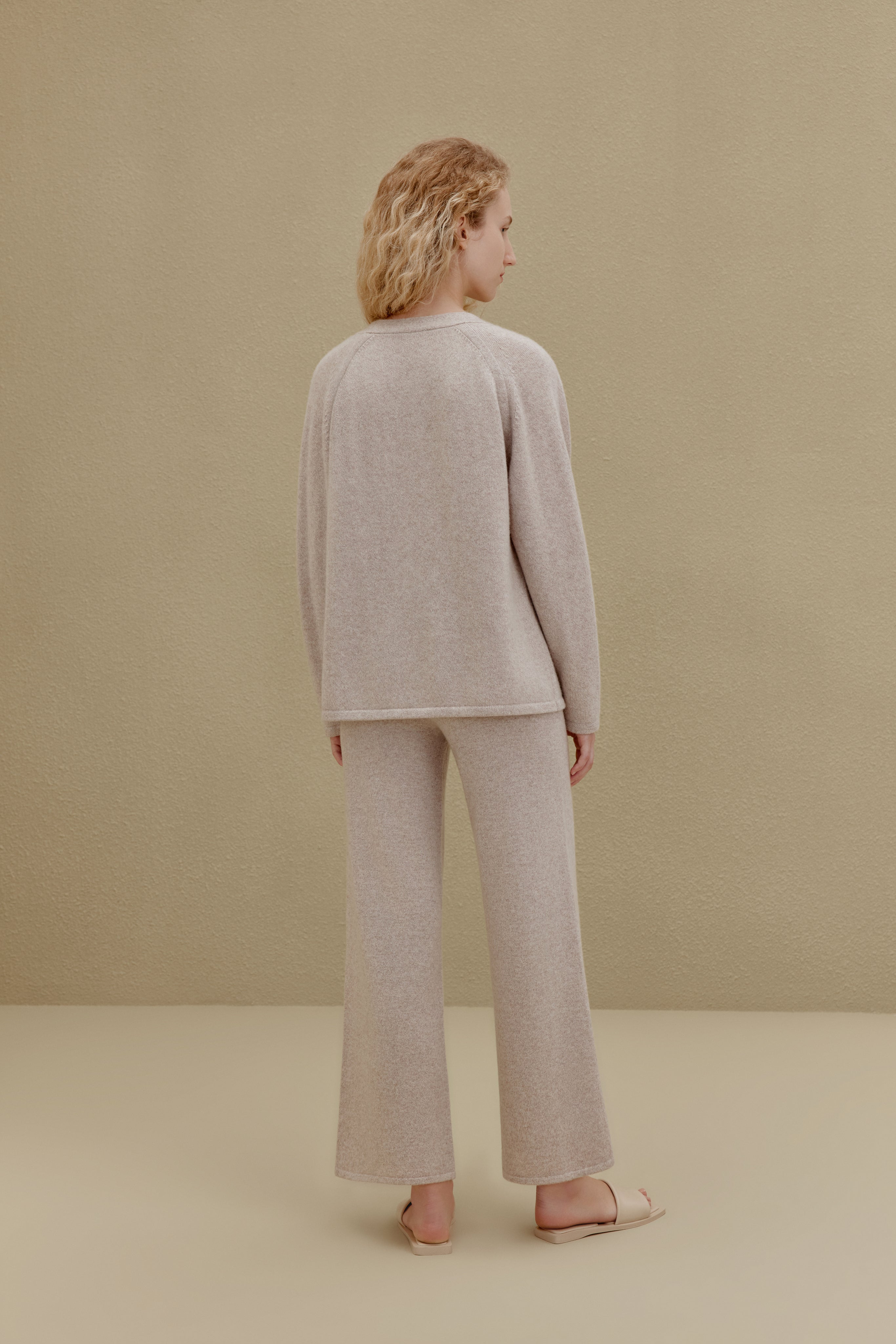 Back view of woman wearing off-white top and wide-leg pants