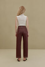 back of woman in white sleeveless top and brown pants