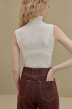 back of woman in white sleeveless top and brown pants