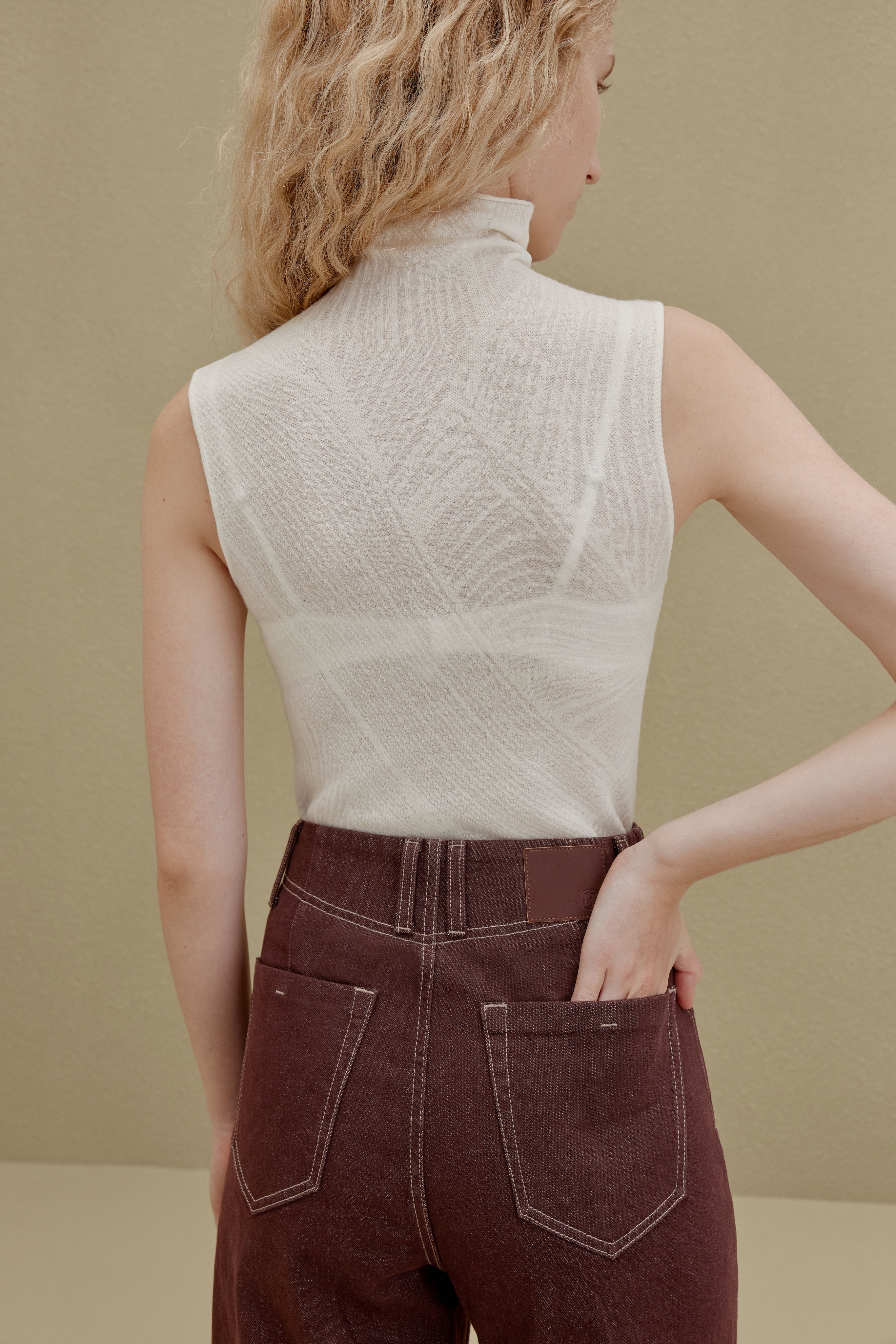 back of woman in white sleeveless top and brown pants