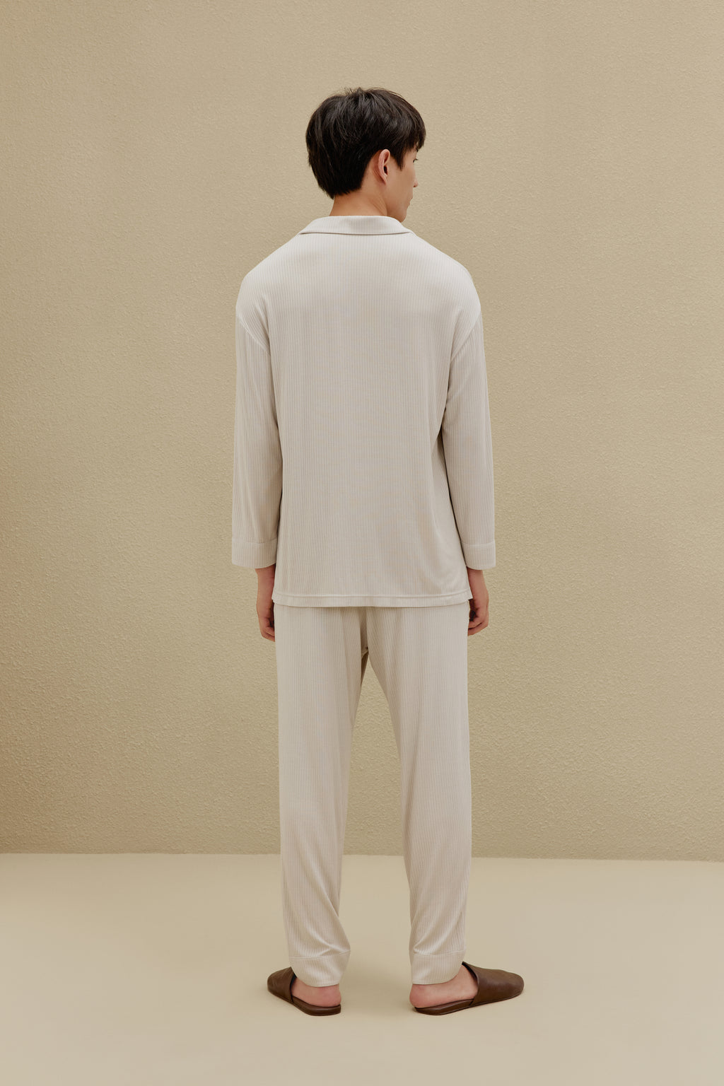 Back view of man in off-white pajamas