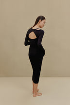back of woman in black long sleeve top and midi skirt