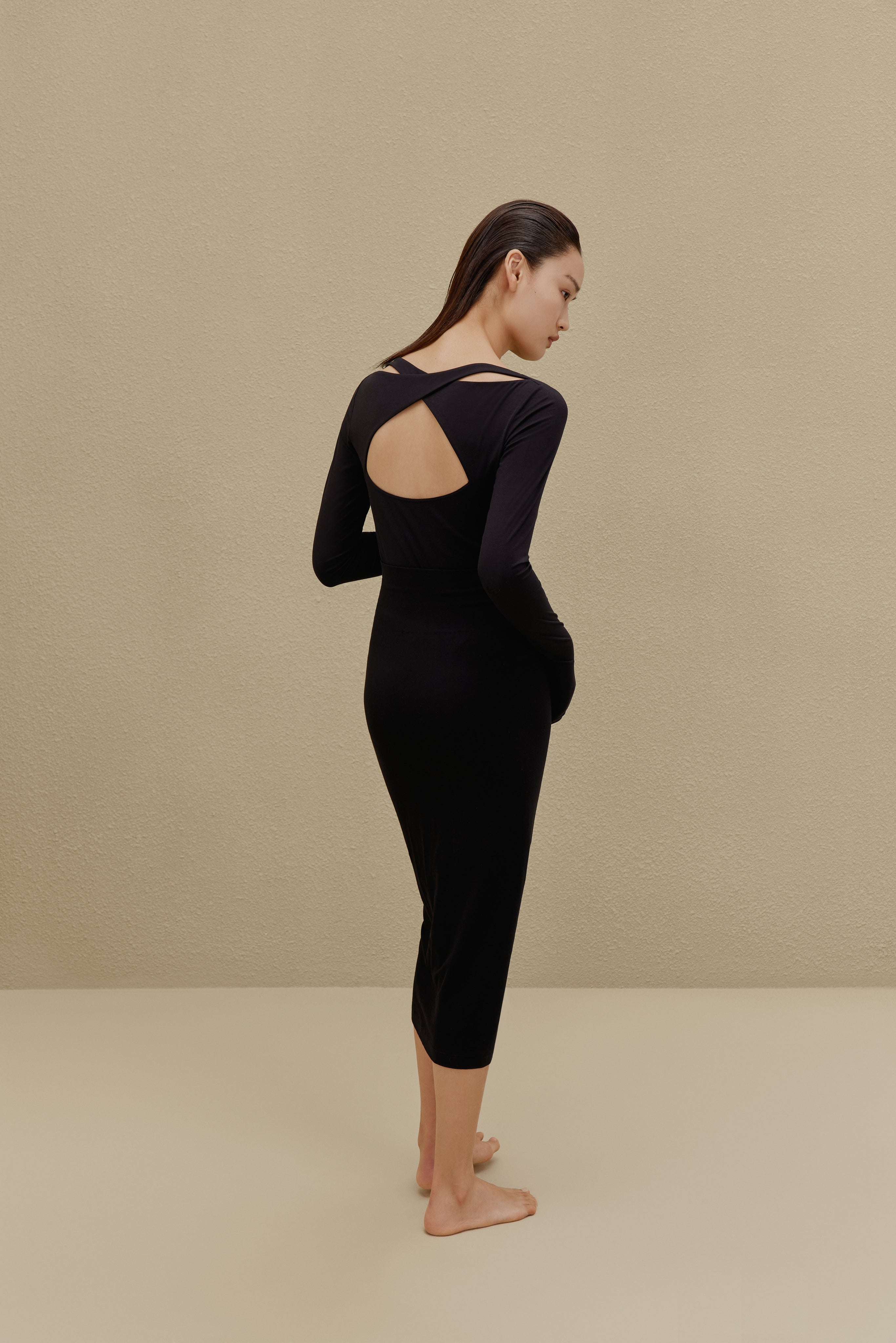 back of woman in black long sleeve top and midi skirt