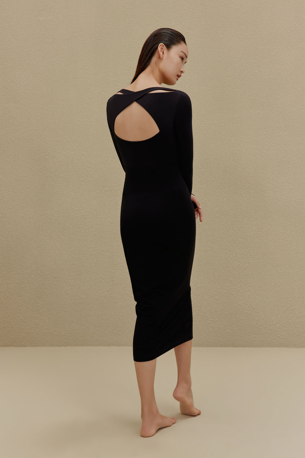 back of woman in black long sleeve top and midi skirt