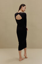 back of woman in black long sleeve top and midi skirt