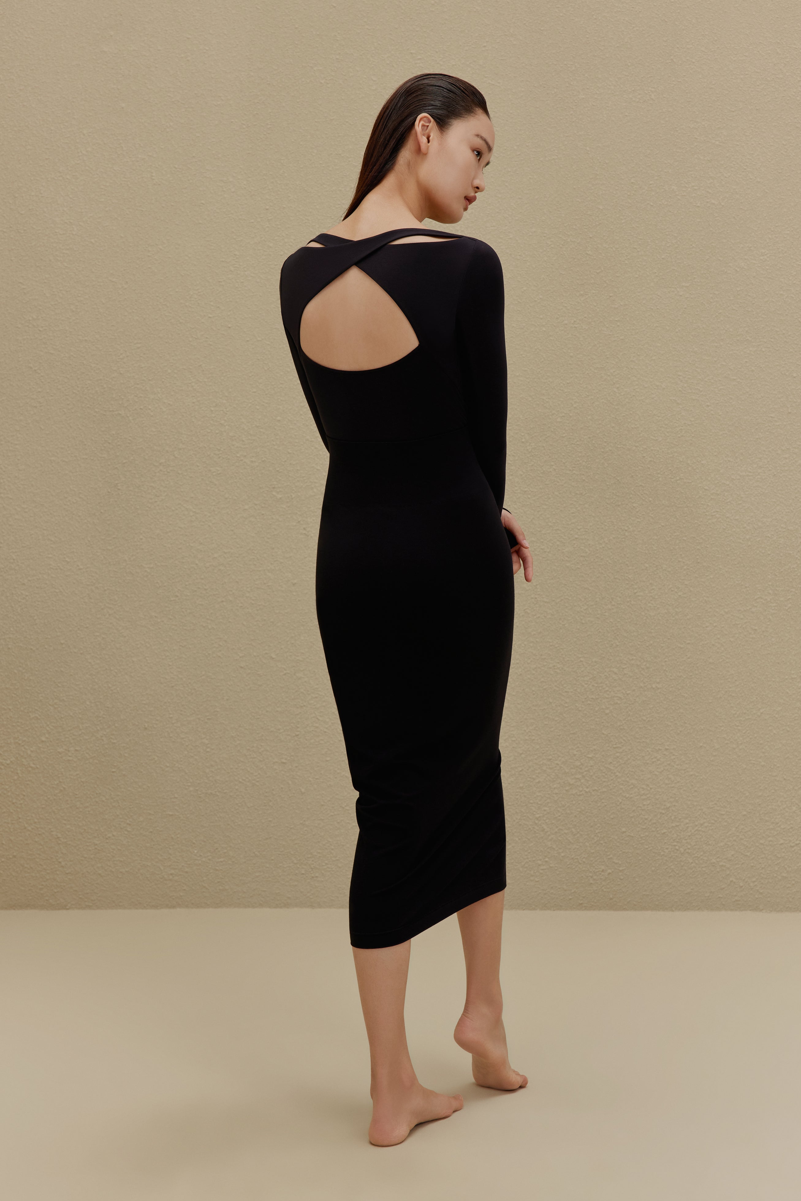 back of woman in black long sleeve top and midi skirt